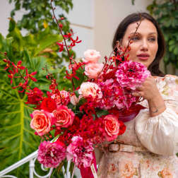 Woman holding a large bouquet of pink and red flowers