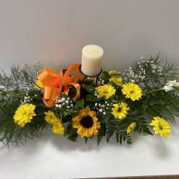Yellow daisy and sunflower arrangement with a candle and orange ribbon