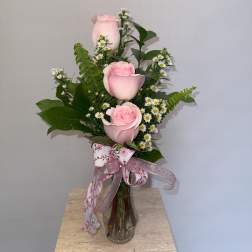 Pink roses arranged in a clear glass vase with small white daisies