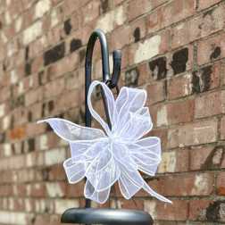 Decorative wind chime with a white bow hanging on a black metal stand