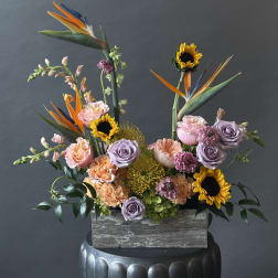 Mixed bouquet with sunflowers, roses, and bird of paradise in a wooden box