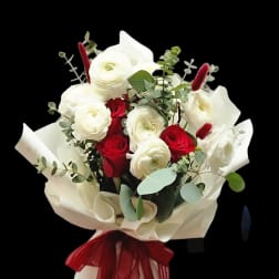 Bouquet of red and white roses wrapped in cream paper with a red ribbon