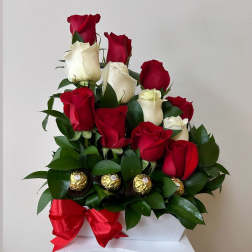Red and white roses arranged with chocolates and a red ribbon