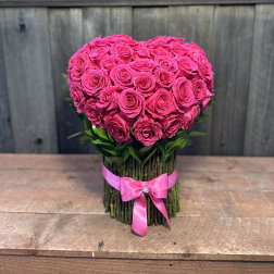 Heart-shaped bouquet of hot pink roses tied with a pink ribbon