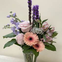 Mixed bouquet of pink and purple flowers in a clear glass vase
