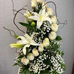 White lilies and cream roses in a white vase with baby's breath