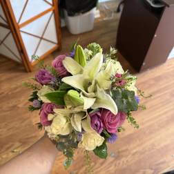 Handheld bouquet of white lilies, pink roses, and purple flowers