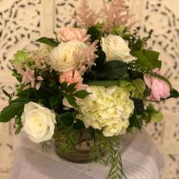 Bouquet of white and blush roses with pale green hydrangea in a vase