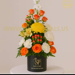 Tall floral arrangement with orange roses, white blooms, and yellow chrysanthemum in a black box