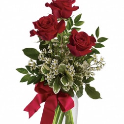 Red roses in a clear glass vase with a red ribbon