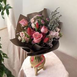 Pink and red mixed bouquet wrapped in dark paper