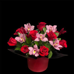 Red roses and pink orchids arranged in a red box