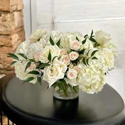 White roses and hydrangeas in a clear glass vase
