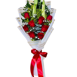 Bouquet of red roses and white lilies wrapped in white paper with a red ribbon
