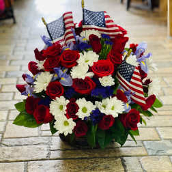 Red roses and white daisies arranged with small American flags