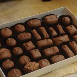 Box of assorted chocolate candies in paper cups