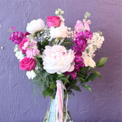 Pink and white bouquet in a clear glass vase with ribbon