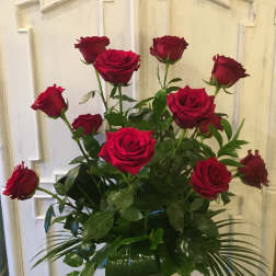 Red roses arranged in a clear glass vase with greenery