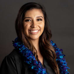 Woman wearing a blue and purple flower lei over a black top