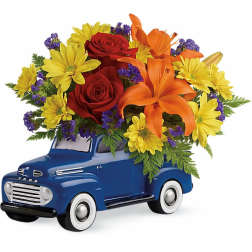 Bouquet of red roses, yellow daisies, and orange lilies in a blue truck container