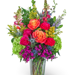 Bright mixed bouquet in a clear glass vase with roses and carnations