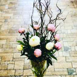 Pink and white peonies in a wine glass vase