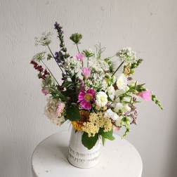 Mixed bouquet in a white ceramic vase with pink, white, and purple flowers