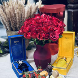 Red rose bouquet in a vase with chocolate-covered strawberries and gift boxes