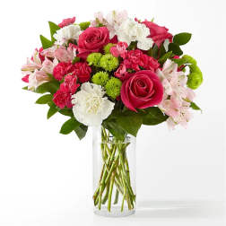 Bouquet of pink roses, carnations, and white flowers in a clear glass vase