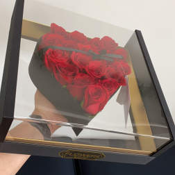 Heart-shaped box of red roses under a clear lid