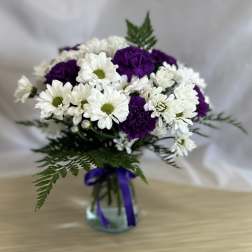 Bouquet of white daisies and purple carnations in a glass vase