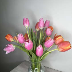 Pink and orange tulips arranged in a clear glass vase