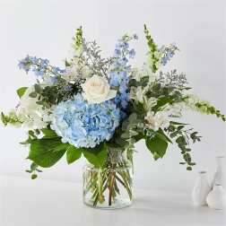 Blue hydrangeas and white roses in a clear glass vase
