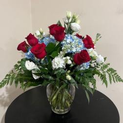 Red roses and blue hydrangeas in a clear glass vase