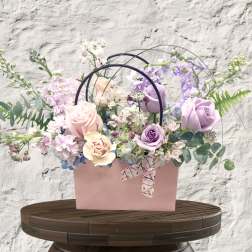 Pastel flower arrangement in a pink box with arched handles