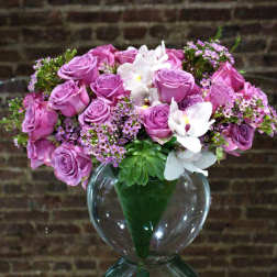 Pink rose bouquet with white orchids in a clear glass vase
