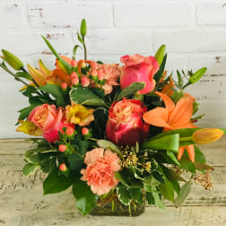 Mixed bouquet of pink roses, lilies, and carnations in a glass vase