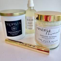 Three scented candles and a room spray arranged on a white surface.