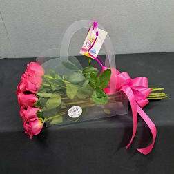 Pink roses in a clear gift bag with a bright ribbon and birthday tag