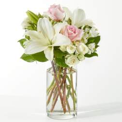 Bouquet of white lilies and pale pink roses in a clear glass vase
