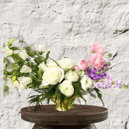 Bouquet of white and pink roses with purple flowers in a gold vase