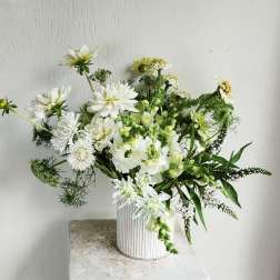 White floral arrangement in a ribbed white vase