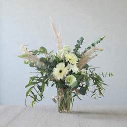White gerbera daisies and greenery in a clear glass vase