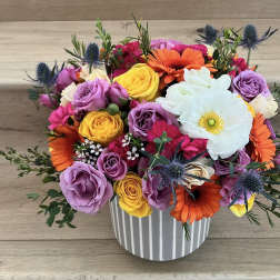 Colorful bouquet of roses, gerbera daisies, and a white anemone in a striped vase