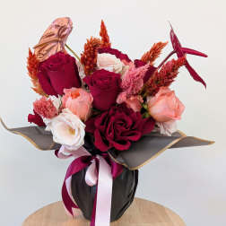 Bouquet of red, pink, and white roses in black wrap with ribbon