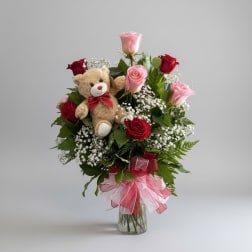 Bouquet of pink and red roses with a teddy bear in a glass vase