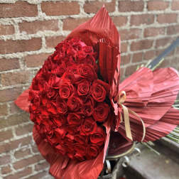 Large bouquet of red roses wrapped in red paper with a ribbon