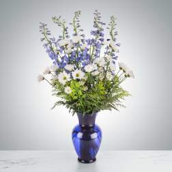 Blue vase with white daisies and purple delphinium
