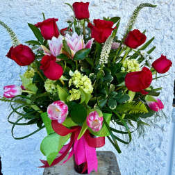 Bouquet of red roses and pink tulips in a glass vase