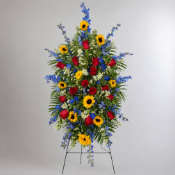 Standing floral spray with red roses, sunflowers, and blue flowers on a metal easel